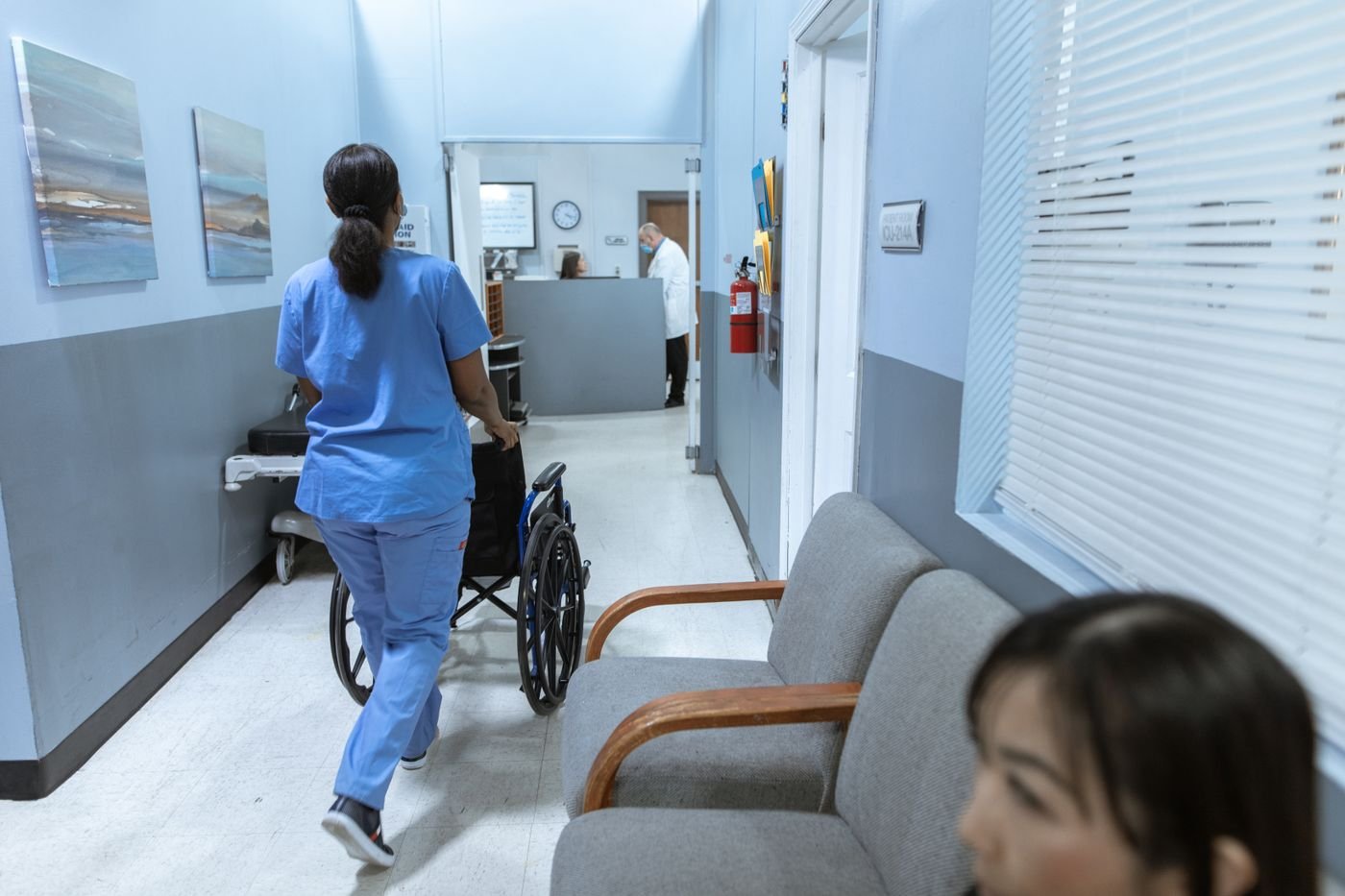 Nurse bringing a wheelchair through a clinic