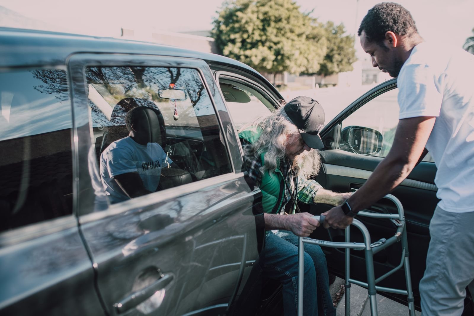 Driver helping an elderly passenger with a walker into a vehicle